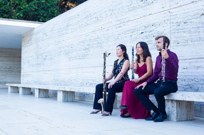 El trío de clarinete tocando en el Pabellón Mies, sonriendo