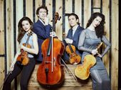 Cuatro miembros del Parallel Quartet posan con sus instrumentos de cuerda ante un fondo de madera: Alfredo Ancillo y Laura V. Hidalgo con violines, Fátima Poblete con viola y Stamen Nikolov con cello.